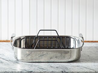 An All-Clad Roaster on a marble tabletop.